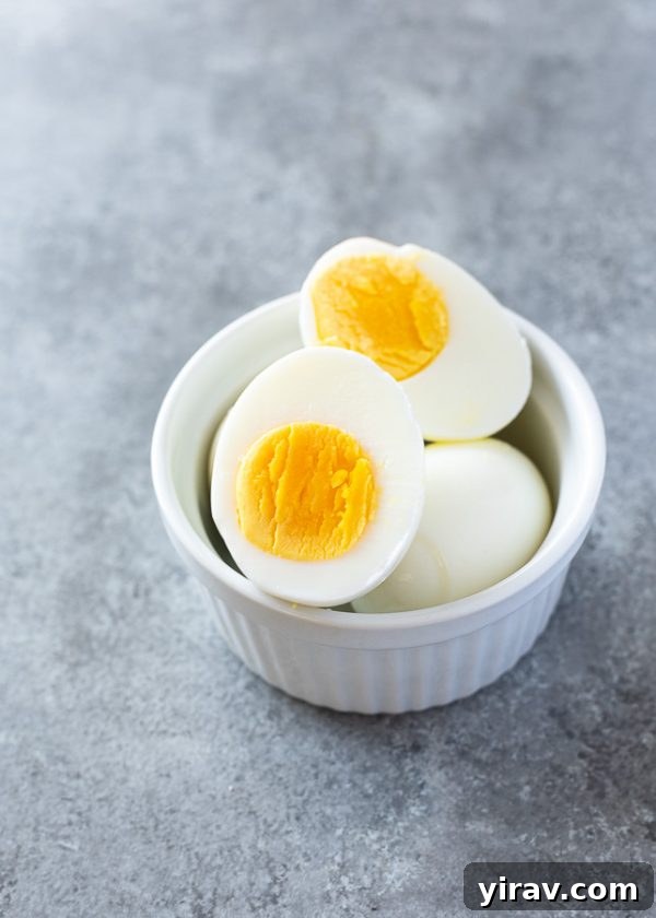 Close-up of perfectly hard boiled eggs in a ramekin, showcasing their smooth texture and readiness for use.