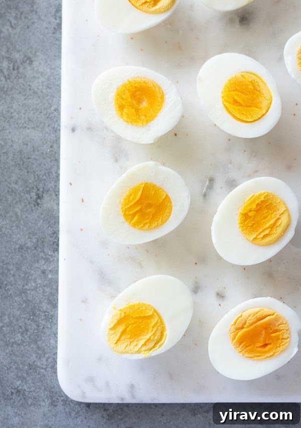 A row of perfectly hard boiled eggs neatly arranged on a marble board, ready to be served or prepared further.