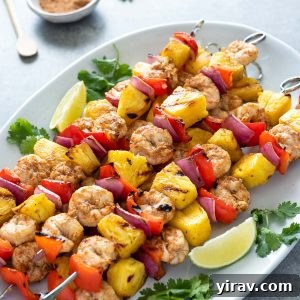 Perfectly grilled pineapple shrimp skewers on a white serving platter, garnished with fresh cilantro and lime wedges.