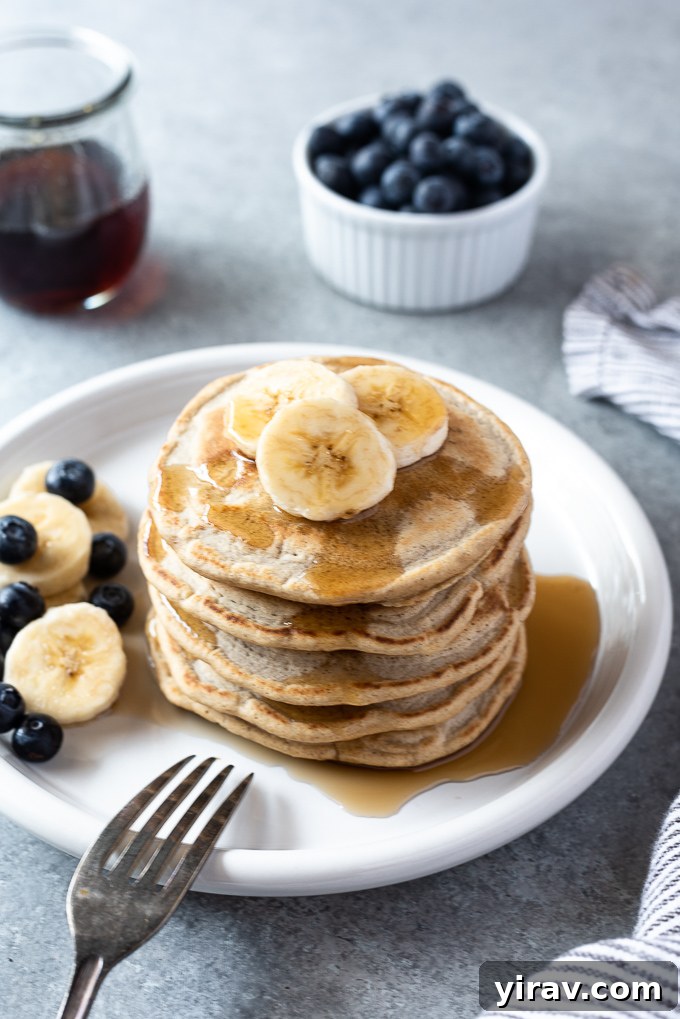 Fluffy oat flour pancakes on a plate with bananas and blueberries