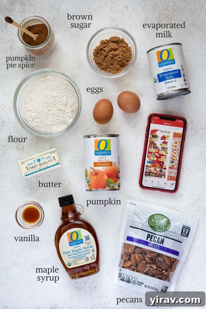 A flat lay of fresh ingredients for Pumpkin Pecan Pie including canned pumpkin puree, evaporated milk, maple syrup, eggs, pumpkin pie spice, vanilla extract, pecans, brown sugar, flour, and butter.