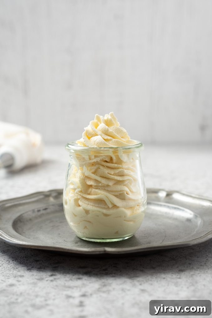 Homemade whipped cream delicately piped into a clear glass jar, ready to serve or garnish desserts.