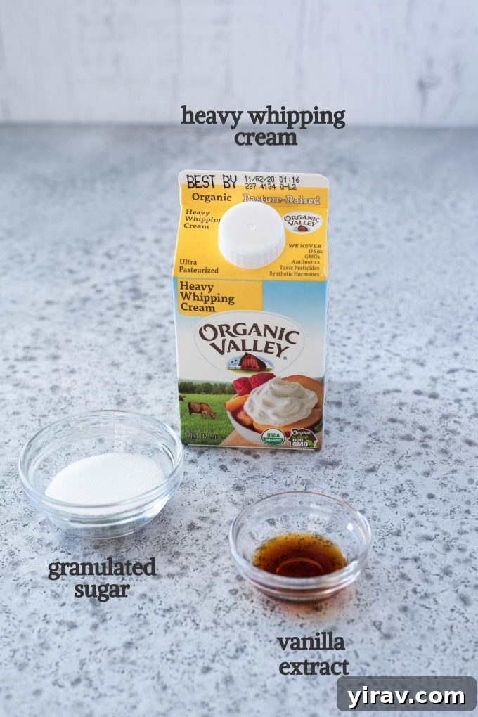 The three essential ingredients for homemade whipped cream: heavy whipping cream, granulated sugar, and vanilla extract, arranged on a surface.