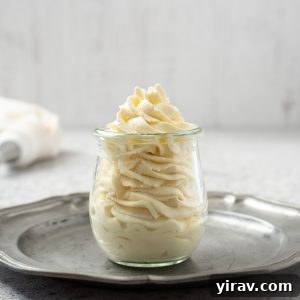 Homemade whipped cream delicately piped into a clear glass jar.