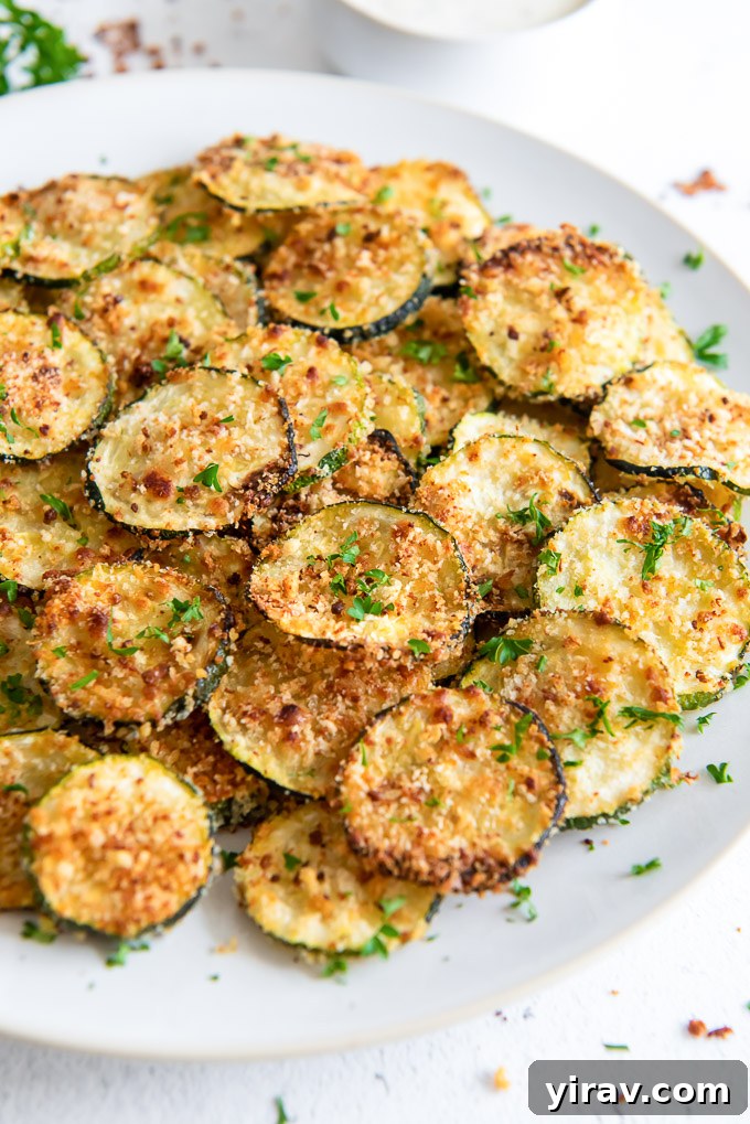 Oven Baked Zucchini Crisps 6 A plate of golden and crispy baked zucchini chips, garnished with fresh parsley.