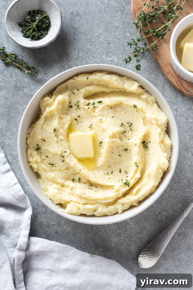 A white bowl filled with creamy parsnip mash, topped with a melting pat of butter and fresh thyme leaves, ready to be served.