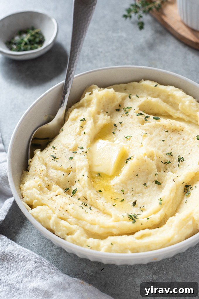 A large white serving bowl of parsnip puree, with a generous pat of butter melting on top, indicating its richness and readiness to serve.