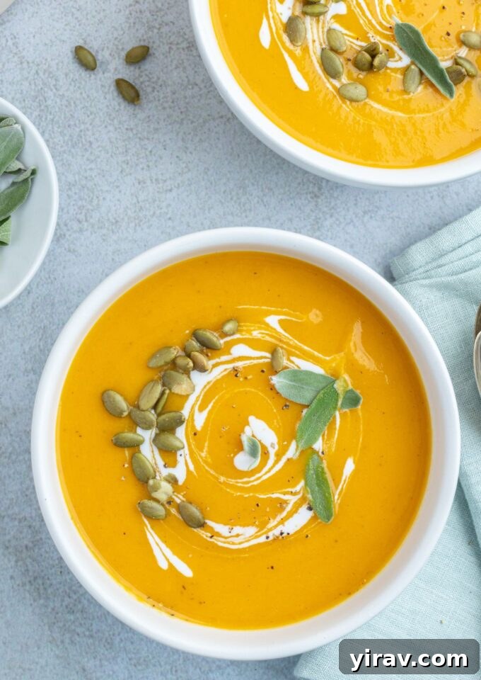 Roasted pumpkin soup in bowls with coconut milk and sage