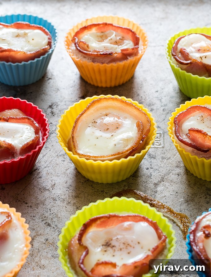 Bacon and egg muffins baking in vibrant silicone molds, showing their golden brown perfection.