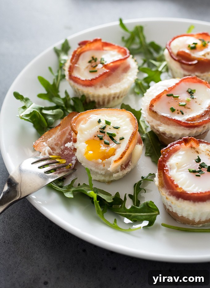 A bacon egg muffin cut in half, revealing a perfectly cooked yolk, with a fork ready to enjoy.