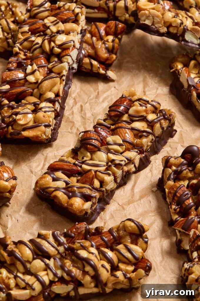 Nut bars drizzled with dark chocolate on parchment paper.