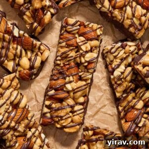 Nut bars covered in dark chocolate on parchment paper.