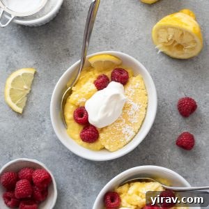 Lemon pudding cake in bowls with raspberries and whipped cream