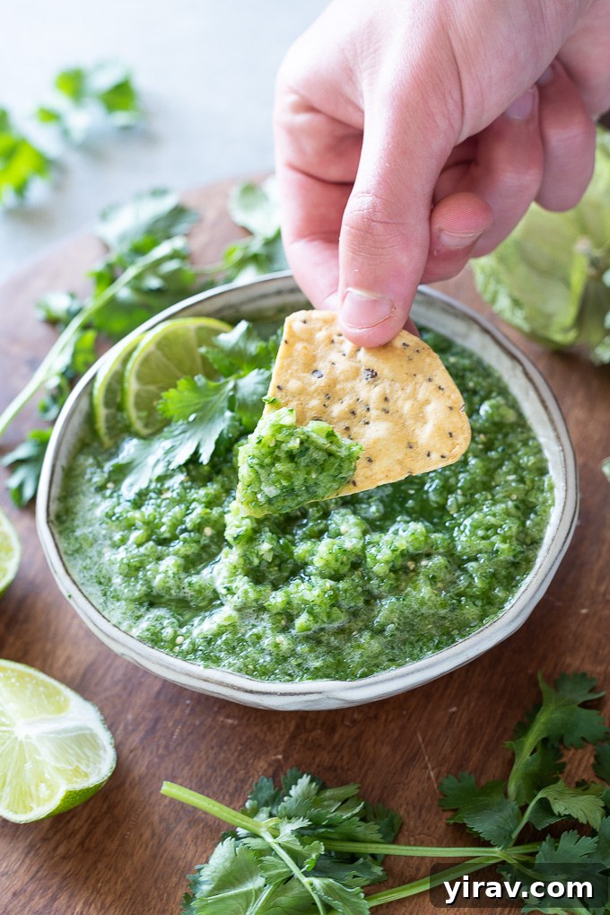 A tortilla chip being dipped into a bowl of fresh tomatillo salsa