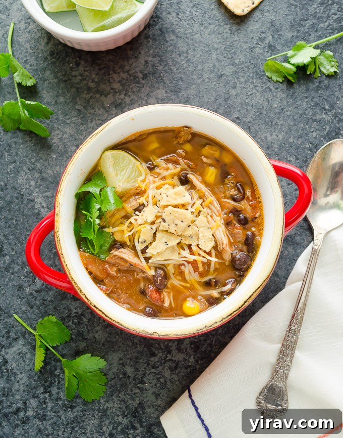 Chicken tortilla soup in a bowl with lime wedges and a spoon