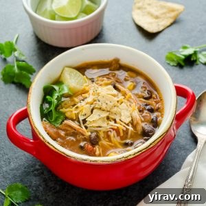 Chicken tortilla soup in a red bowl with chips and cilantro