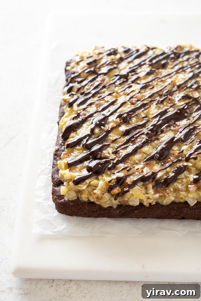 German Chocolate Cake Brownies 8 Close-up of frosted German chocolate brownies, showcasing the thick layer of coconut pecan frosting and ganache drizzle, ready to be sliced.