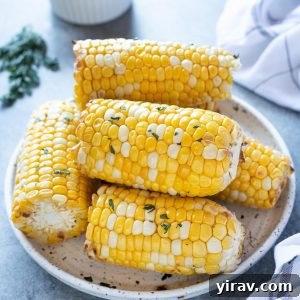 Golden Air Fryer Corn 8 Air fryer corn on the cob piled on a white plate