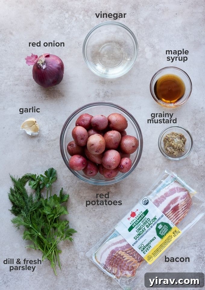 A flat lay of fresh ingredients for German potato salad including red baby potatoes, bacon, red onion, garlic, vinegar, maple syrup, grainy mustard, parsley, and dill.