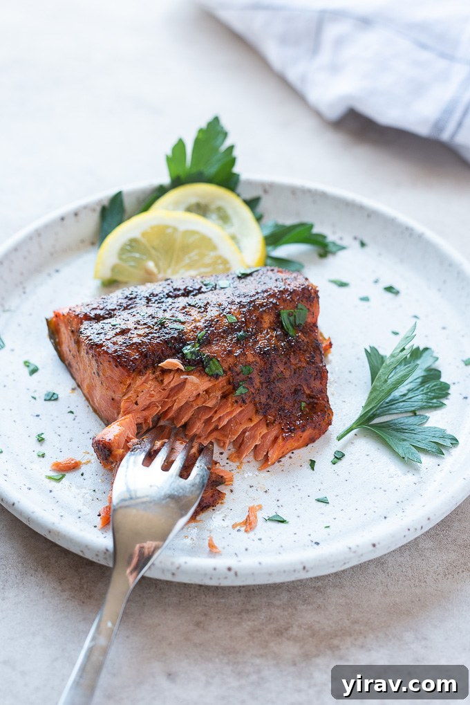 Effortless Air-Fried Salmon 7 A fork cutting into a perfectly cooked air fryer salmon fillet, showing its flaky texture