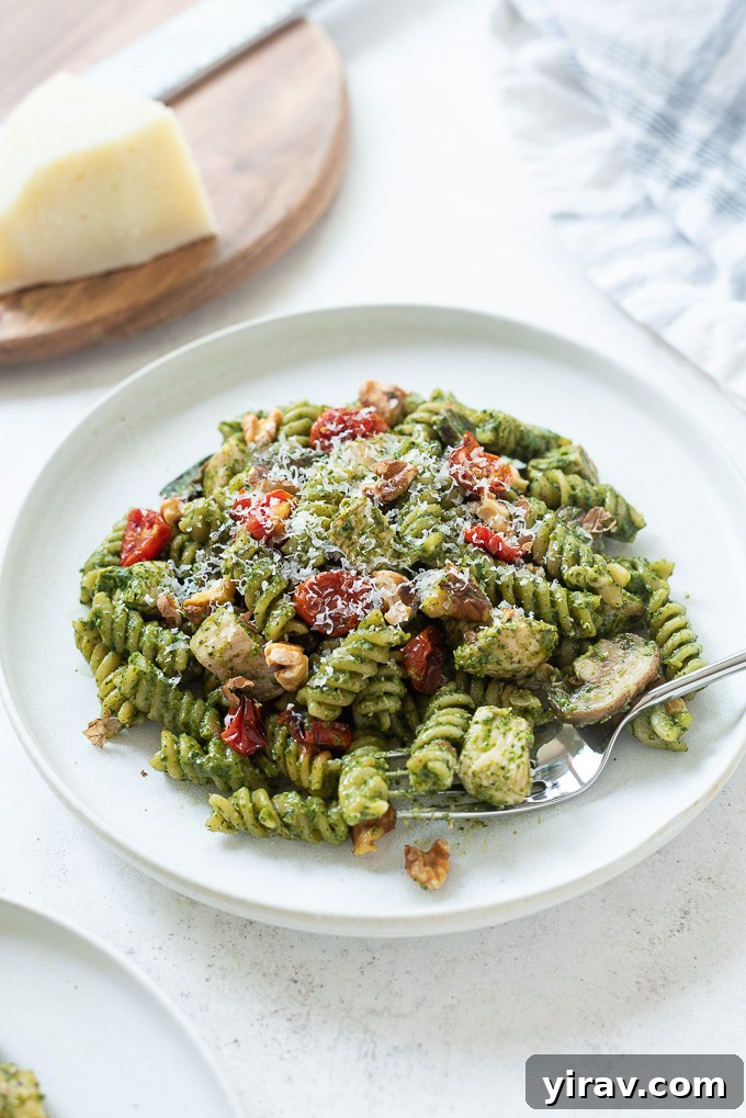 Plate of chicken pesto pasta with a fork digging in, showing a portion ready to eat.