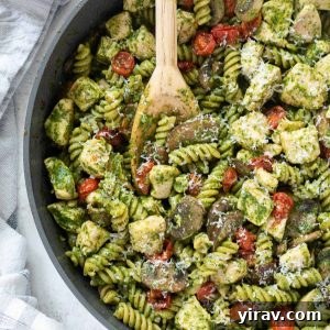 Chicken pesto pasta in a skillet with wooden spoon