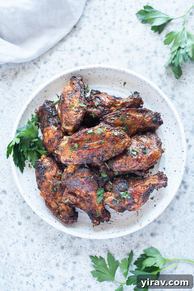 Air Fryer Wings: Crispy Perfection 3 Close-up of crispy air fryer chicken wings on a white plate with a sprig of parsley