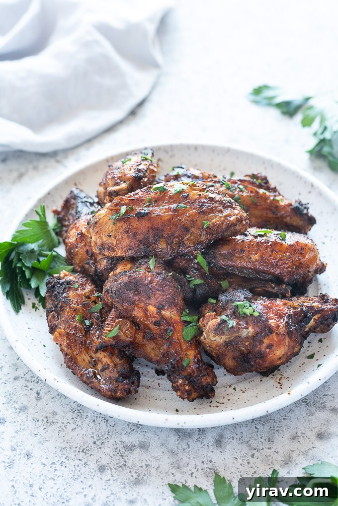 Air Fryer Wings: Crispy Perfection 5 Air fryer chicken wings on a white plate with fresh parsley, ready to serve