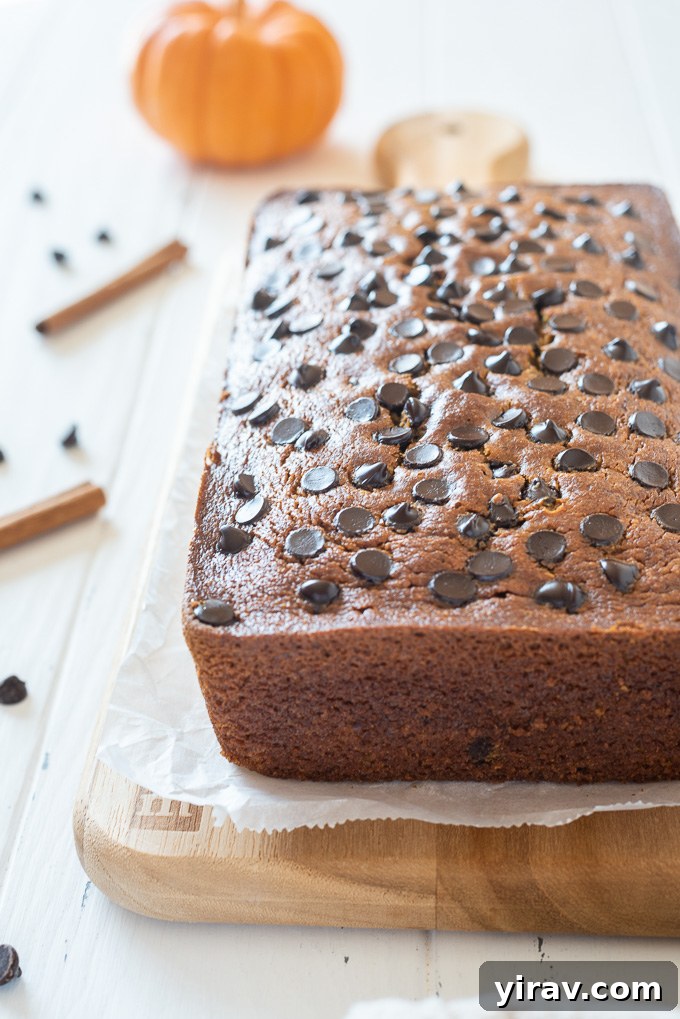 A perfectly baked loaf of gluten-free pumpkin bread resting on a wooden cutting board, showcasing its golden crust and inviting appearance.