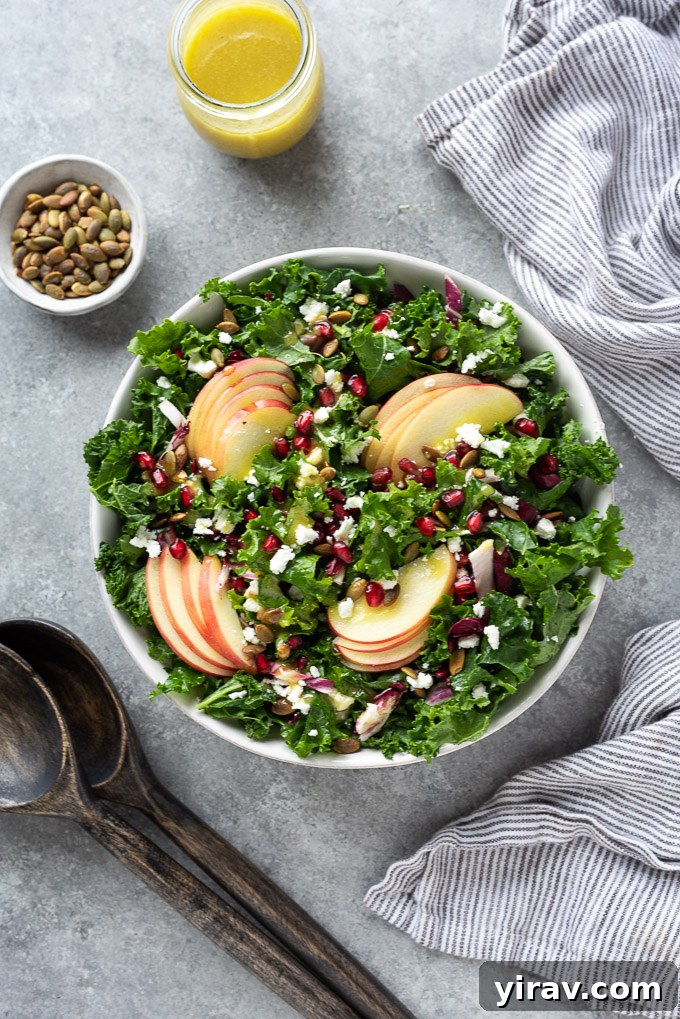 Kale apple salad in a serving bowl with salad servers, ready to be enjoyed.