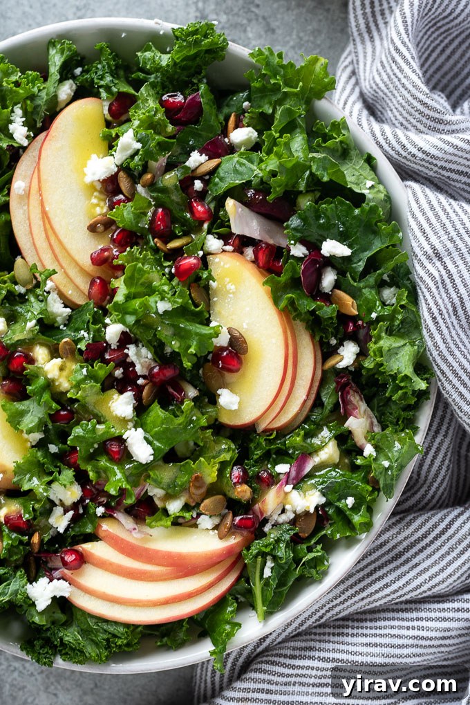 Kale and apple salad with pomegranate in a serving bowl, showcasing fresh ingredients.