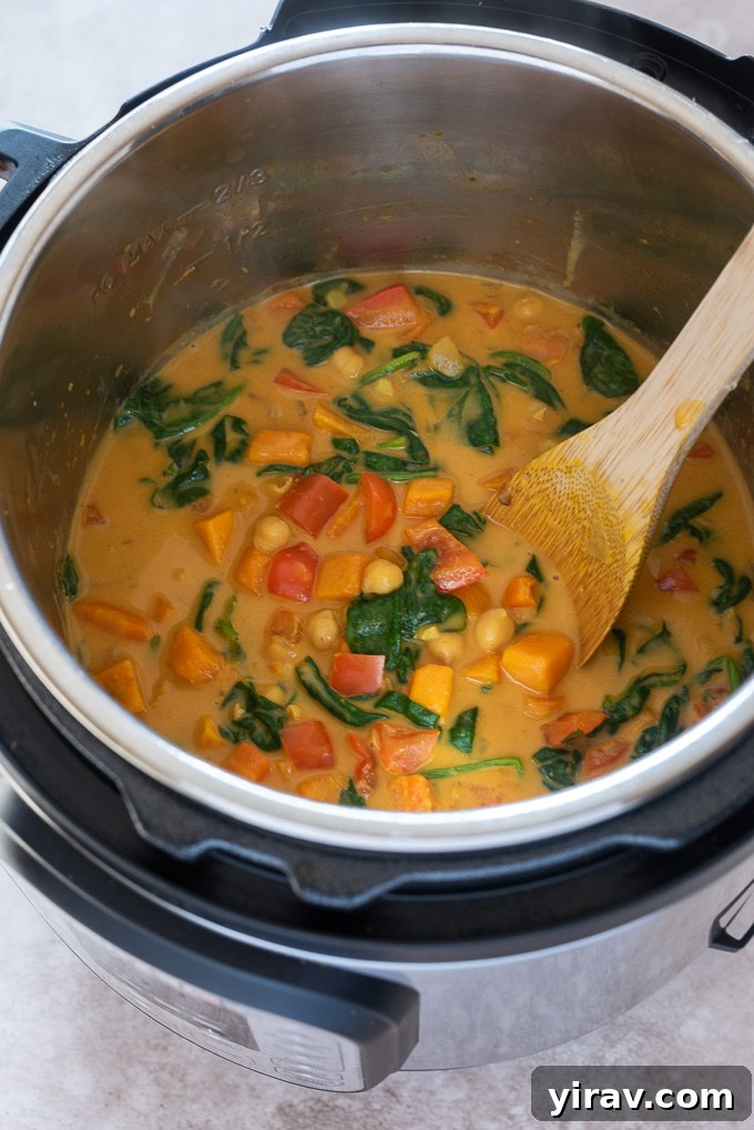 Close-up shot of creamy sweet potato chickpea curry simmering inside an Instant Pot, showing the rich texture and vibrant colors of the ingredients.