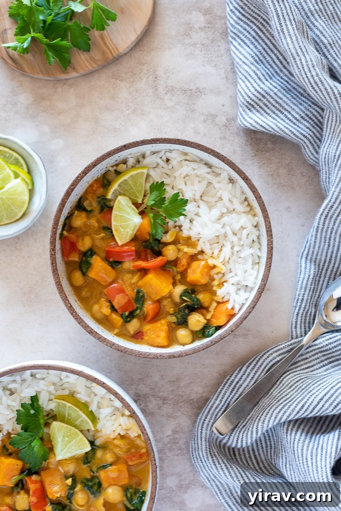 A visually appealing bowl of chickpea curry, served with a side of rice, garnished with lime and cilantro, ready to be enjoyed.
