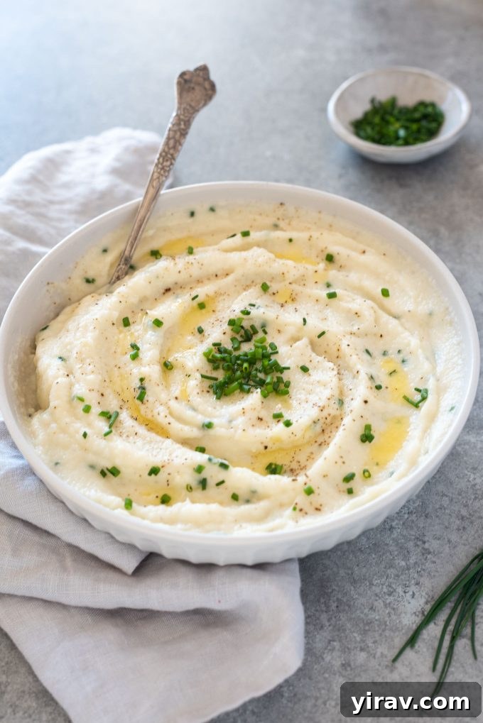 Creamy Garlic Mashed Cauliflower 2 A beautifully presented bowl of creamy garlic mashed cauliflower, ready to be served, with a spoon digging in to show its smooth texture.