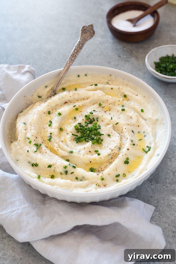 Creamy Garlic Mashed Cauliflower 7 A close-up shot of creamy garlic mashed cauliflower in a white bowl, showing its inviting texture and flecks of chives.