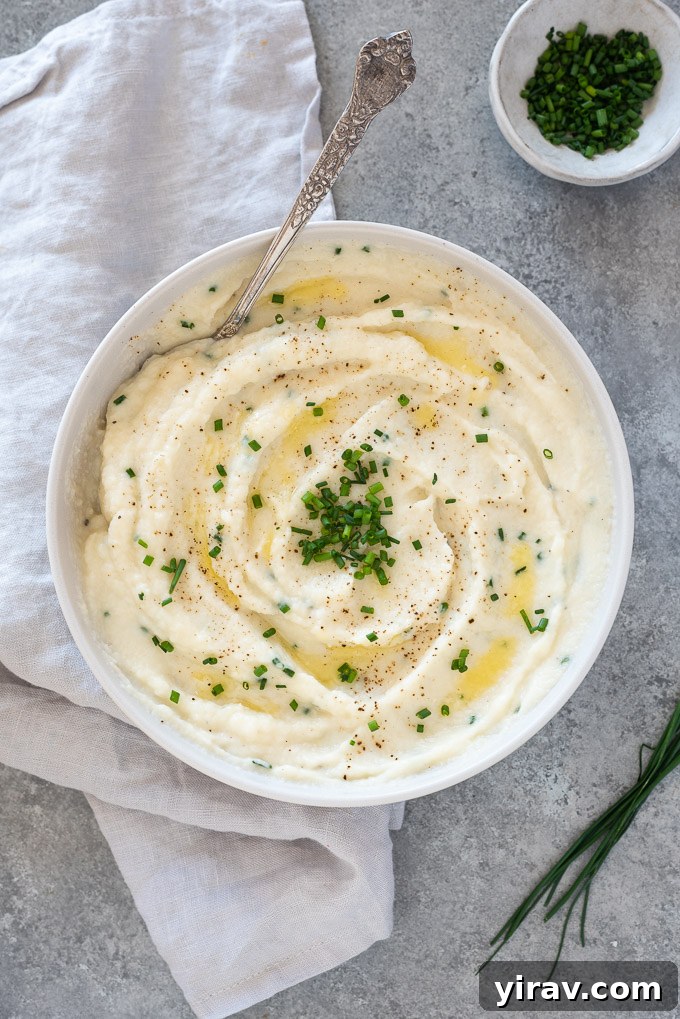 Creamy Garlic Mashed Cauliflower 8 A serving of garlic mashed cauliflower in a bowl, topped with a pat of melting butter and a sprinkle of fresh chives, inviting indulgence.