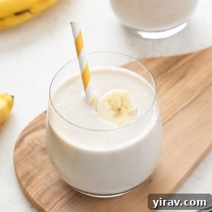 Banana smoothie in a glass with straw and banana slice