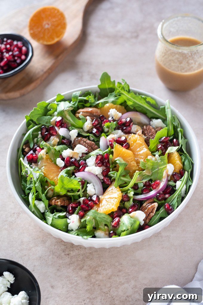 Arugula Citrus Jewel Salad 7 Arugula orange pomegranate salad in a white bowl with pecans on top