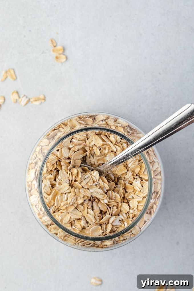 Homemade Oat Flour: Simple & Quick 4 A glass jar filled with old-fashioned rolled oats, with a wooden spoon resting inside.