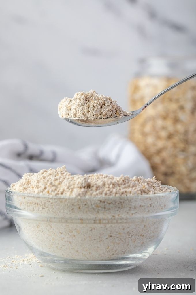 Homemade Oat Flour: Simple & Quick 7 A spoonful of freshly made oat flour being held over a bowl, highlighting its fine, powdery texture.