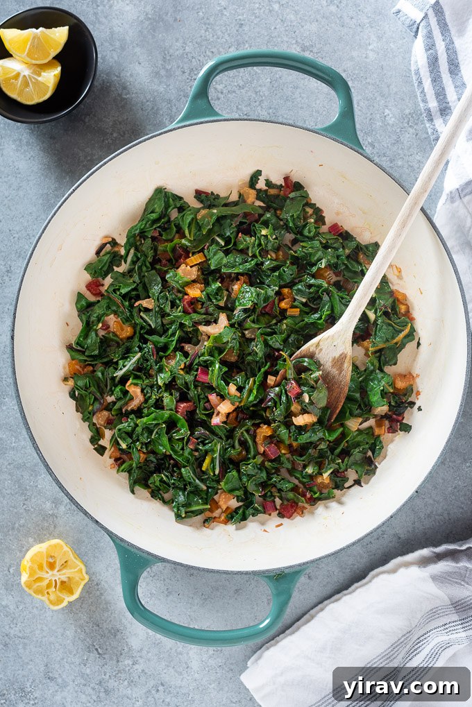 Garlicky Sautéed Swiss Chard 3 A close-up shot of sautéed rainbow Swiss chard simmering in a Dutch oven, highlighting its vibrant colors and tender texture.
