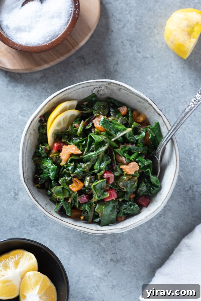 Garlicky Sautéed Swiss Chard 8 A serving of sautéed Swiss chard in a white bowl, with a fork poised to take a bite, highlighting its appealing texture and vibrant green.