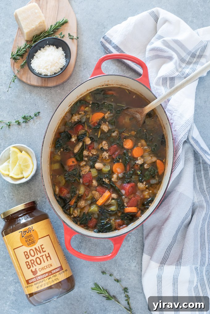 Italian sausage kale soup simmering gently in a rustic Dutch oven on the stove.