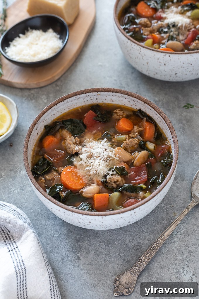 A bowl of Italian sausage kale soup topped with grated Parmesan cheese, ready to be enjoyed.