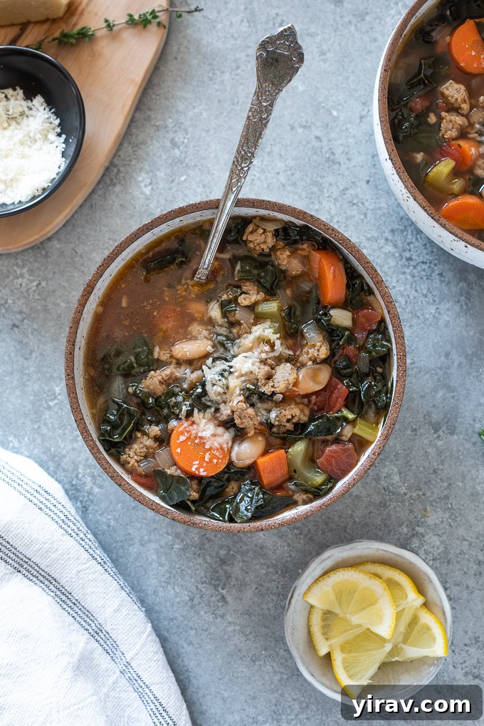 A spoon buried deep inside a bowl of Italian sausage kale soup, showcasing the abundant ingredients.