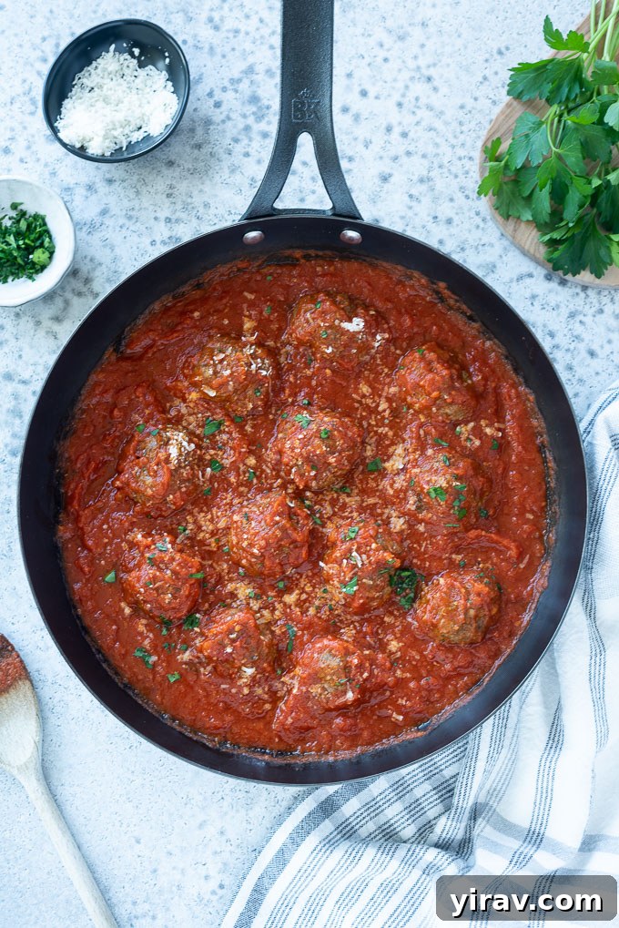 Simple Oven Roasted Meatballs 3 Close-up of perfectly browned oven baked Italian meatballs in a skillet, coated in a rich red sauce.
