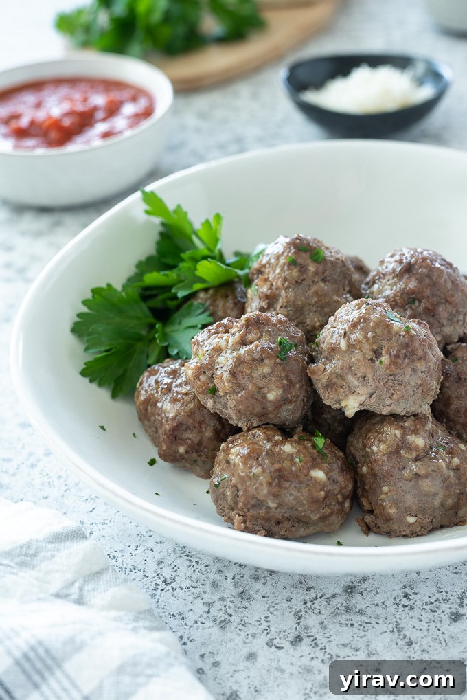 Simple Oven Roasted Meatballs 6 A white bowl filled with cooked ground beef meatballs, garnished with fresh parsley.