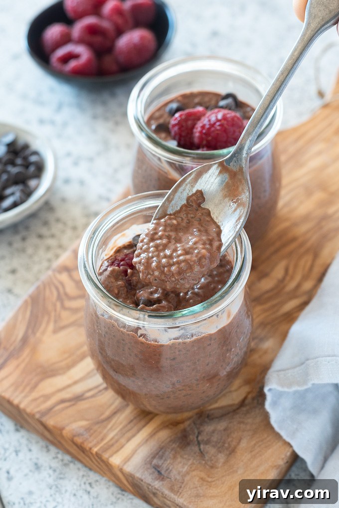 Spoonful of rich chocolate chia seed pudding being lifted over a jar, showing its creamy texture
