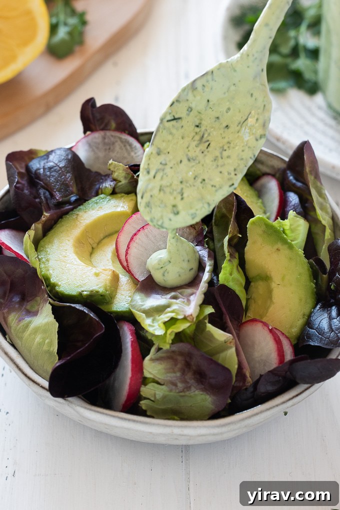 The Perfect Green Goddess Dressing 8 Green Goddess dressing being drizzled generously onto a fresh salad, illustrating serving idea.