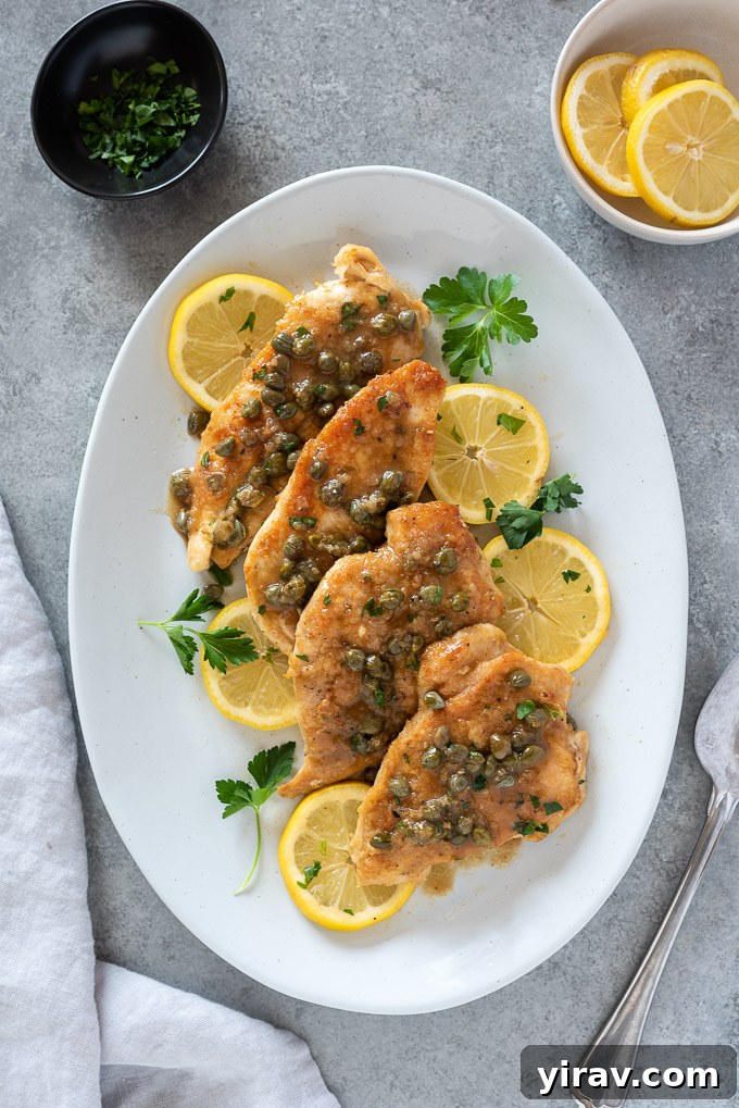 Deliciously Simple Chicken Piccata 3 Chicken piccata served on a white platter, generously covered in lemon caper sauce.
